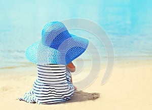 Pretty little girl in striped dress and straw hat enjoying sea