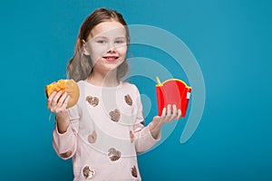 Pretty, little girl in sweater with brunet hair hold a burger