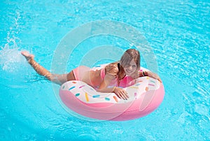 Pretty little girl swimming in outdoor pool and have a fun with inflatable circle