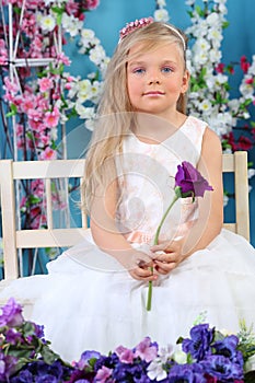 Pretty little girl in white dress sits and holds photo