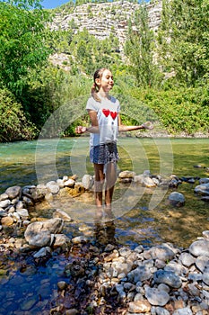 Pretty little girl in a white t-shirt wetting her feet in the cool waters of the Mijares River