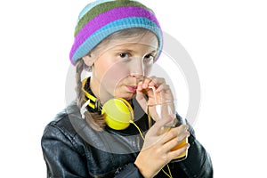 a pretty little girl with a woolen cap drinking a glass of orange juice