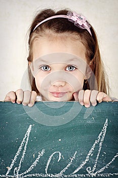 Pretty little girl writing on the blackboard