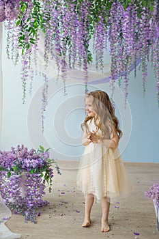 Pretty little girl in a yellow dress in a room decorated a lilacs