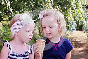 Pretty little girls (sisters) eating ice cream in the summer the
