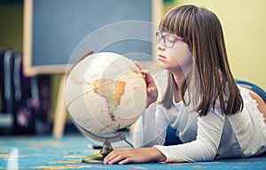 Pretty little student girl studying geography with globe in a child's room