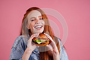 Pretty long redhead ginger girl eyes closed from pleasure eating fries chicken and burger with fried french potatoes in
