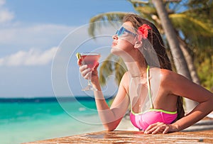 pretty longhaired woman with delicious cocktail by the beach. Maldives