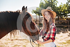 Pretty lovely cowgirl taking care of her horse on ranch