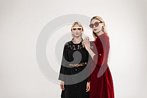 Pretty lovely sexy fashionable young women with fashionable sunglasses wearing vintage dress in room. Studio portrait two fashion
