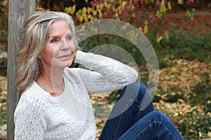 Pretty mature 65+ woman sitting on bench leaning hand on face