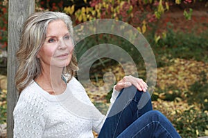 Pretty mature 65+ woman sitting on bench outdoors looking off camera