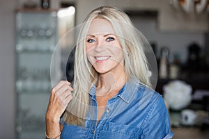 Pretty mature woman model smiling at the camera in her kitchen.