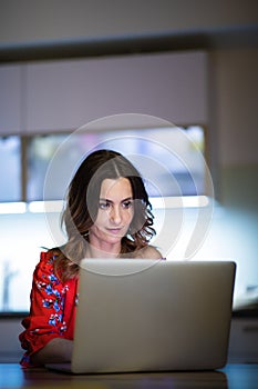 Pretty, mid-aged woman burning the midnight oil, working online