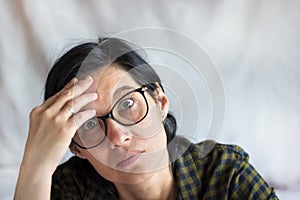 A pretty middle-aged brunette with glasses looks thoughtfully at the camera. A surprised, questioning look. Emotions.