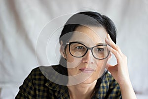 A pretty middle-aged brunette with glasses looks thoughtfully at the camera. A surprised, questioning look. Emotions.