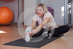 Pretty Middle aged woman does stretching after a workout.