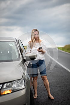 Pretty middle aged woman having car troubles