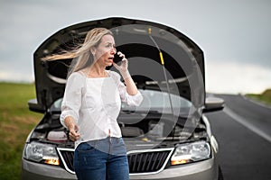 Pretty middle aged woman having car troubles