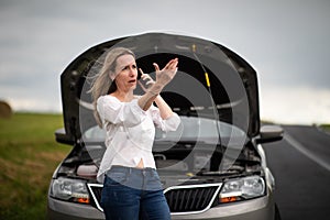 Pretty middle aged woman having car troubles