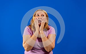 Pretty middle aged woman with her hands on her face with a scare gesture isolated on blue studio background