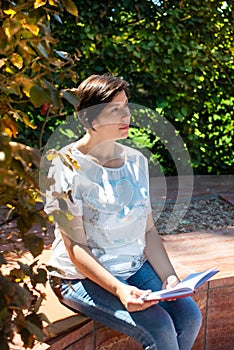 Pretty middle-aged woman sits on a park bench with a notepad. work online in retirement. lifestyle