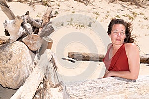 Pretty middle aged woman on a tropical beach with wooden driftwood