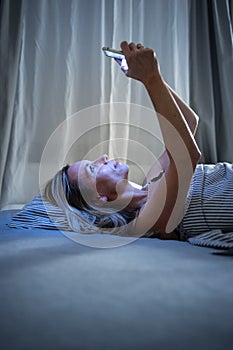 Pretty, middle-aged woman using her tablet computer before sleep in bed