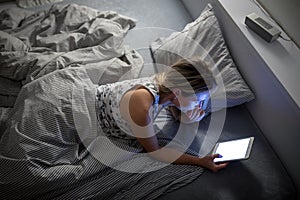 Pretty, middle-aged woman using her tablet computer before sleep in bed