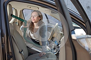 Pretty, middle aged woman vacuum cleaning the interior of a  car