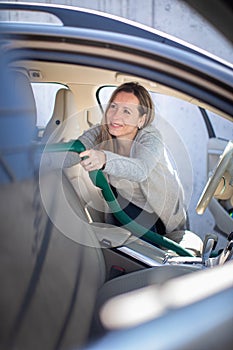 Pretty, middle aged woman vacuum cleaning the interior of a car