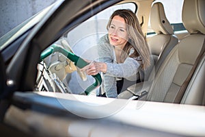 Pretty, middle aged woman vacuum cleaning the interior of a  car