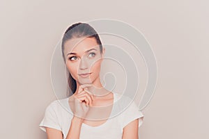 Pretty minded young woman dreaming on gray background