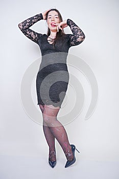 Pretty mix raced plus size girl in elegant black lace midi dress on white studio background