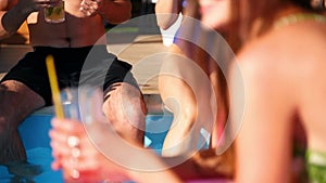 Pretty mixed race woman in stylish sunglasses, swimsuit chilling on pink inflatable flamingo, drinking cocktail of straw