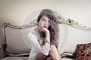 Pretty model girl sitting on victorian sofa posing