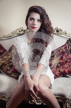 Pretty model girl sitting on victorian sofa posing