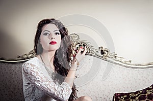 Pretty model girl sitting on victorian sofa posing