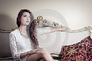 Pretty model girl sitting on victorian sofa posing