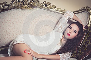 Pretty model girl sitting on victorian sofa posing