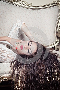 Pretty model girl sitting on victorian sofa posing