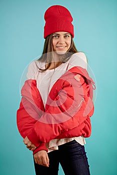 Pretty model is wearing red down-padded coat and read cap. ready to winter