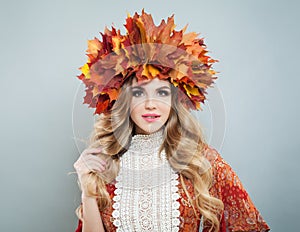 Pretty model woman witn long curly hair, makeup and colorful autumn leaves, studio portrait