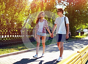 Pretty modern young couple in love walking in sunny summer day