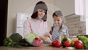 Pretty mother and daughter preparing tasty food at kitchen.