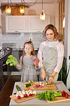 pretty mother and kid girl preparing healthy food for family, vegan salad