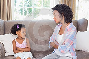 Pretty mother sitting on couch with petulant daughter