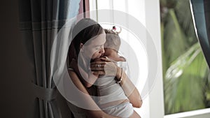 Pretty mother soothing and hugging crying baby girl.