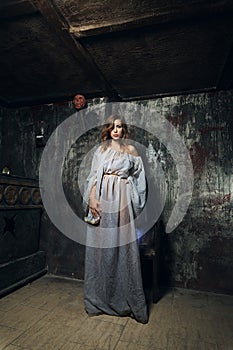 Pretty mystic lady in gothic white dress in underground dungeon