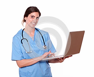 Pretty nurse smiling while using her laptop